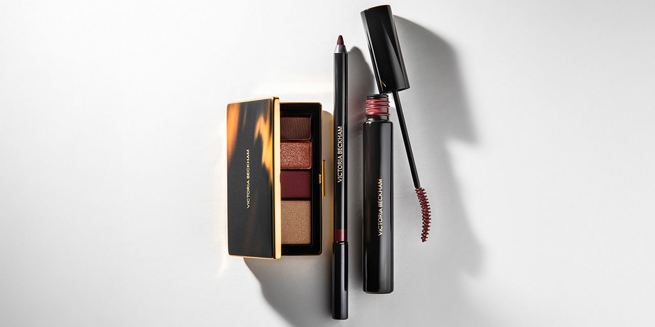 Victoria Beckham Beauty products: eyeshadow palette, lip liner, and mascara, displayed on a light surface.