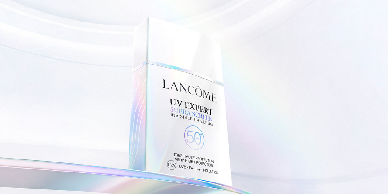 Lancome UV Expert sunscreen bottle on a reflective surface, highlighting its SPF 50+ protection.