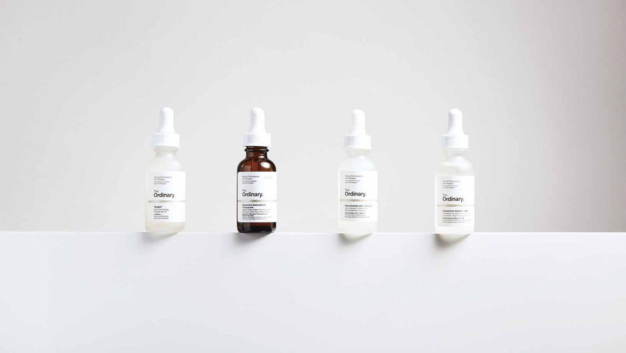 Four of The Ordinary products on a narrow white ledge with a white background