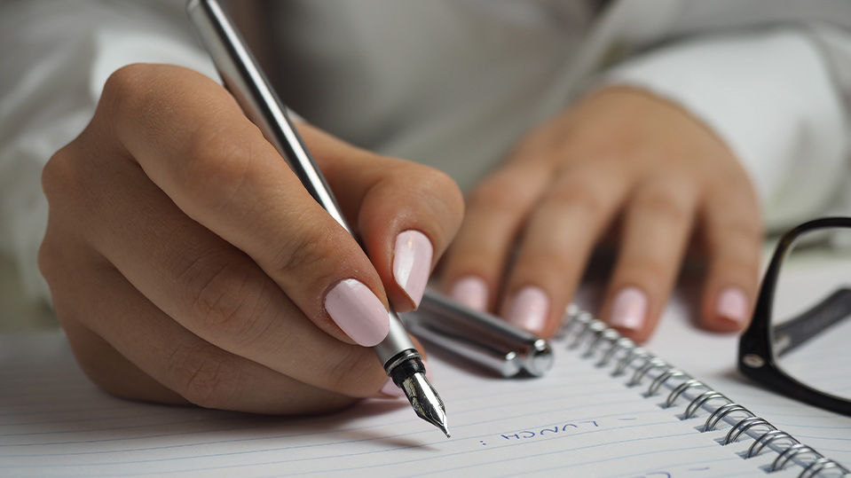 close up of woman's hands writing a note